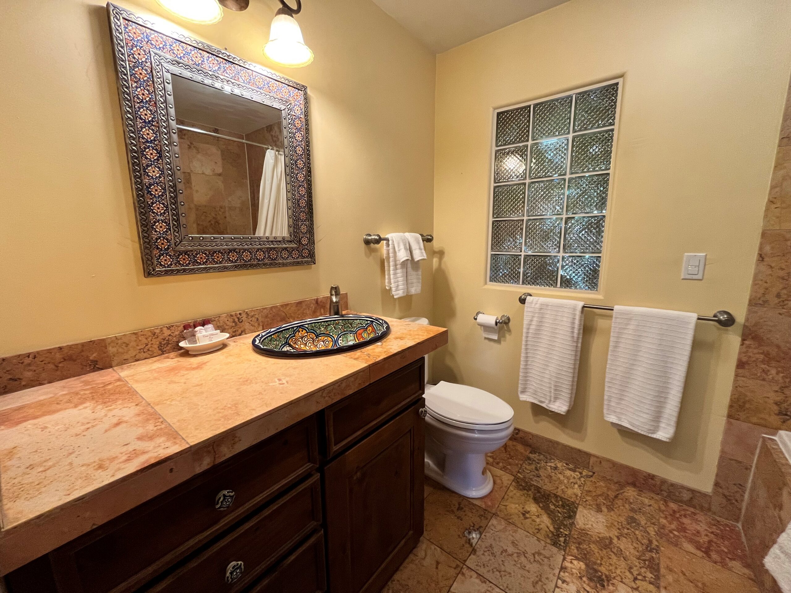 Bathroom vanity with travertine countertops and hand painted Mexican sink.
